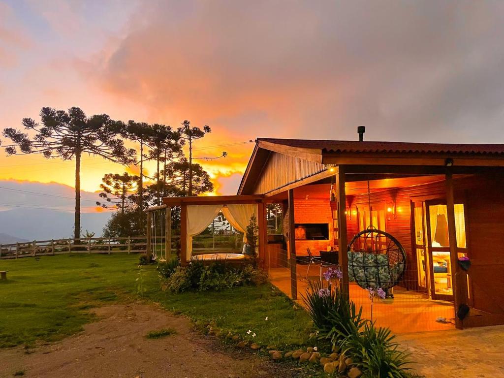 una pequeña casa con una puesta de sol en el fondo en Chalé Casa de campo para família!, en Urubici