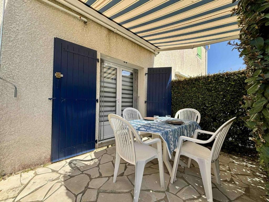 une table avec des chaises blanches et un chiffon de table bleu dans l'établissement Studio charmant à La Cotinière proche plages et commerces, terrasse privée, parking inclus - FR-1-246A-291, à Saint-Pierre-dʼOléron