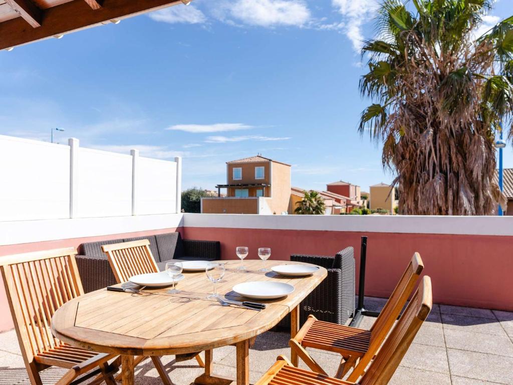 une table et des chaises en bois sur un balcon dans l'établissement Villa climatisée avec terrasse, cuisine d’été et WIFI – Proche plage à Narbonne - FR-1-409-261, à Narbonne