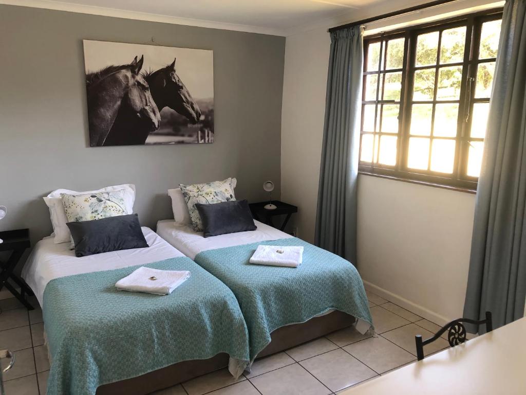 1 dormitorio con 2 camas y una foto de caballo en la pared en Faithlands Self-Catering Cottages, en Port Elizabeth