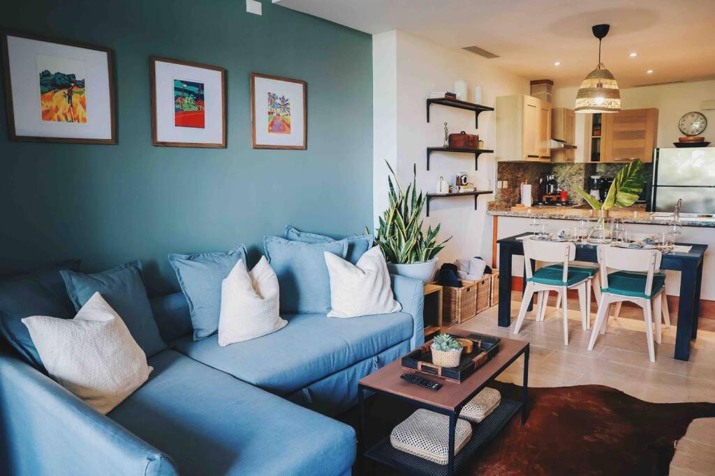 a living room with a blue couch and a kitchen at Modern Condo in Casa de Campo in La Romana