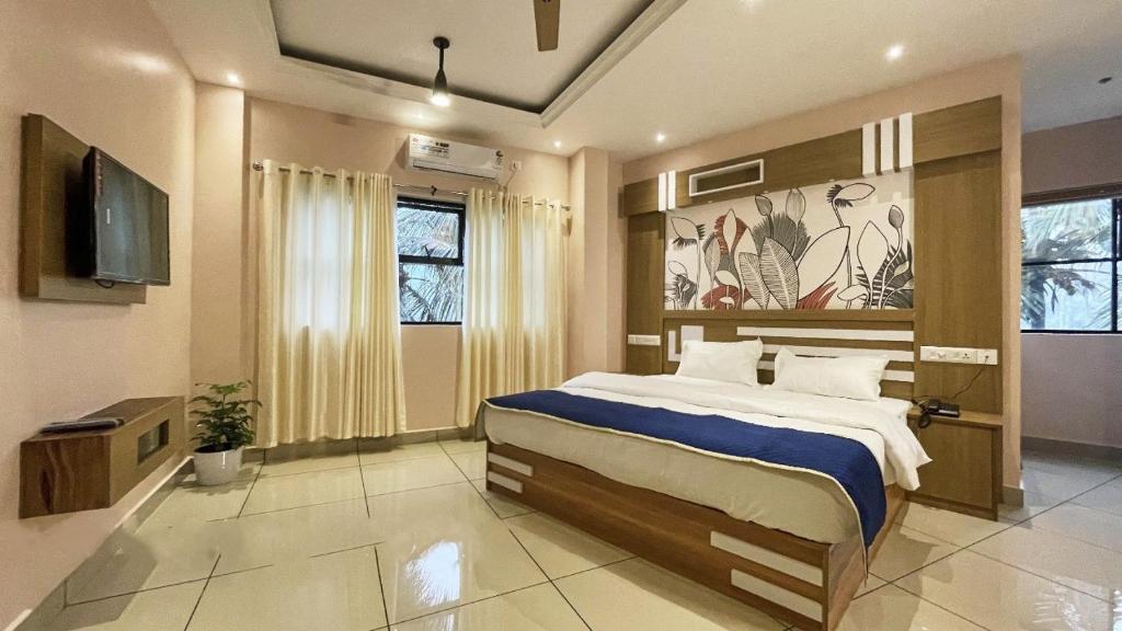 een slaapkamer met een groot bed en een televisie bij IvyArk Residency in Pinangode