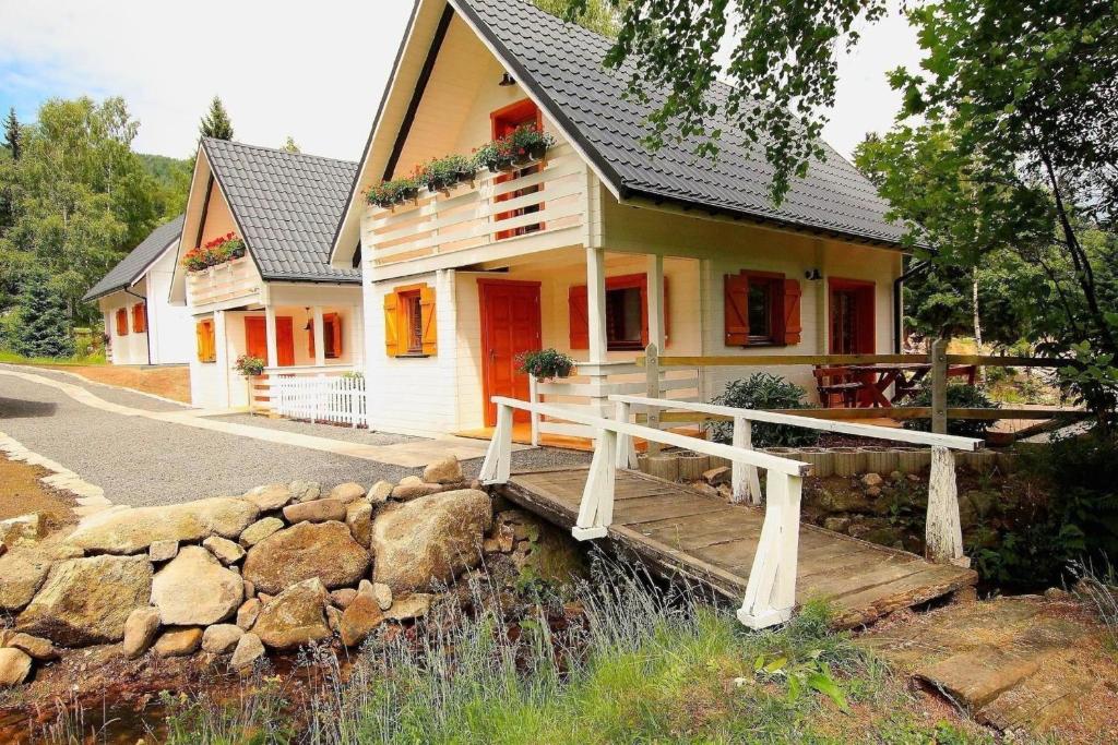 a house with a wooden bridge in front of it at Gemütliche BERGHüTTE-2 am Bach mit Zugang zur Sauna, heißen Badewanne und Pool in Szklarska Poręba