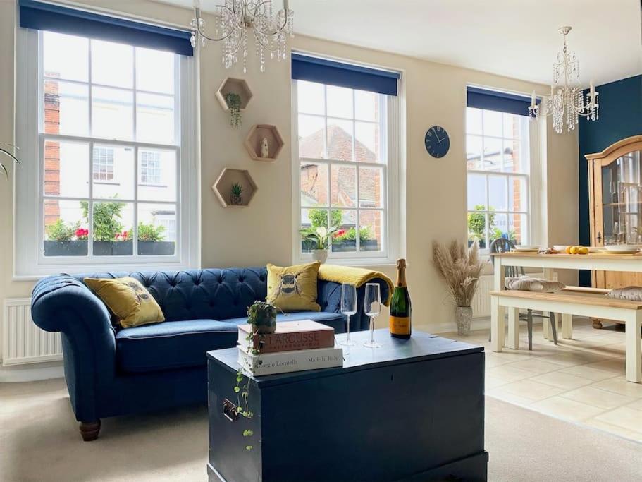 a living room with a blue couch and windows at Elegant, Luxury Family Apartment! Marlow Town Centre, Walk to Pubs in Buckinghamshire