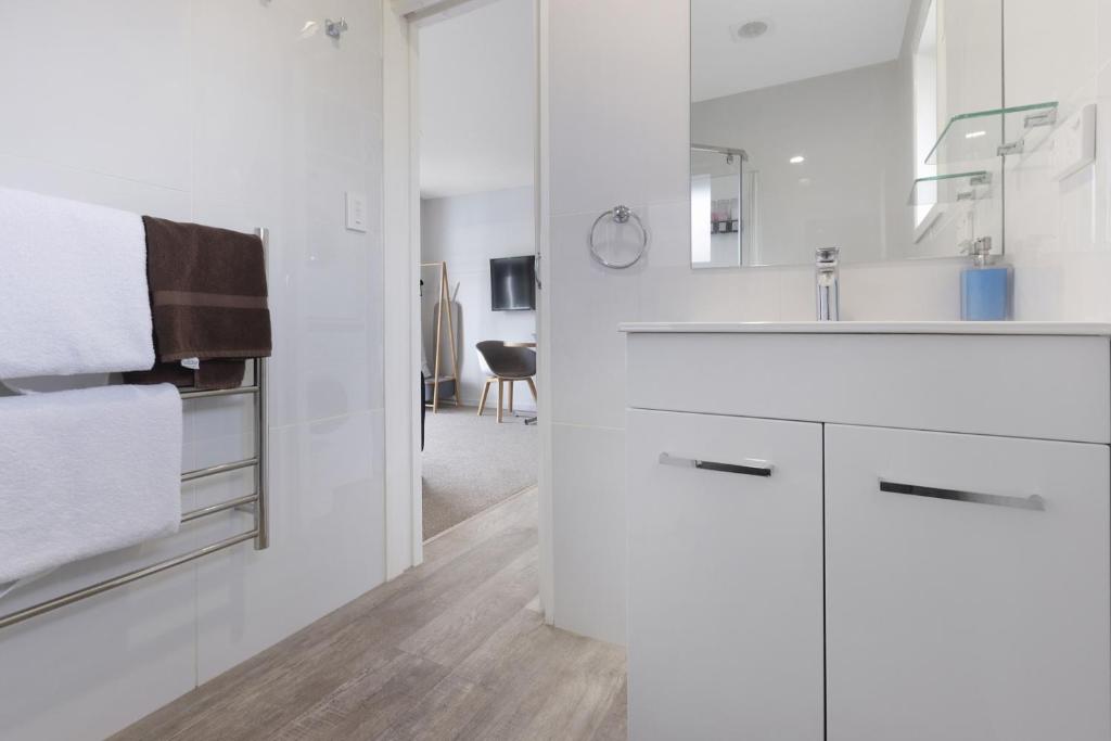 a white kitchen with a sink and a mirror at Adelphi Motel in Christchurch