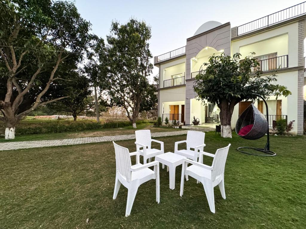 a group of white chairs and a table in front of a house at Golden Mango By Food Bunglow in Rāmnagar