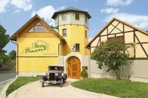 ein altes Auto, das vor einem gelben Gebäude parkt in der Unterkunft Hotel Piccolo in Schleiz