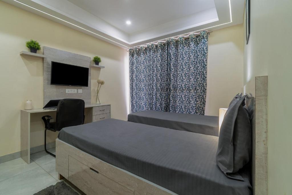 a bedroom with two beds and a desk with a computer at Wandr Serpens - Sector 51, Near Artemis hospital, Unitech Cyber Park in Gurgaon