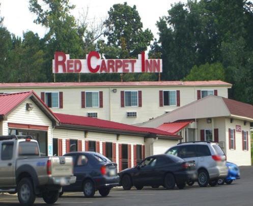 zajazd z czerwonym dywanem z samochodami zaparkowanymi przed nim w obiekcie Red Carpet Inn Syracuse Airport w mieście North Syracuse