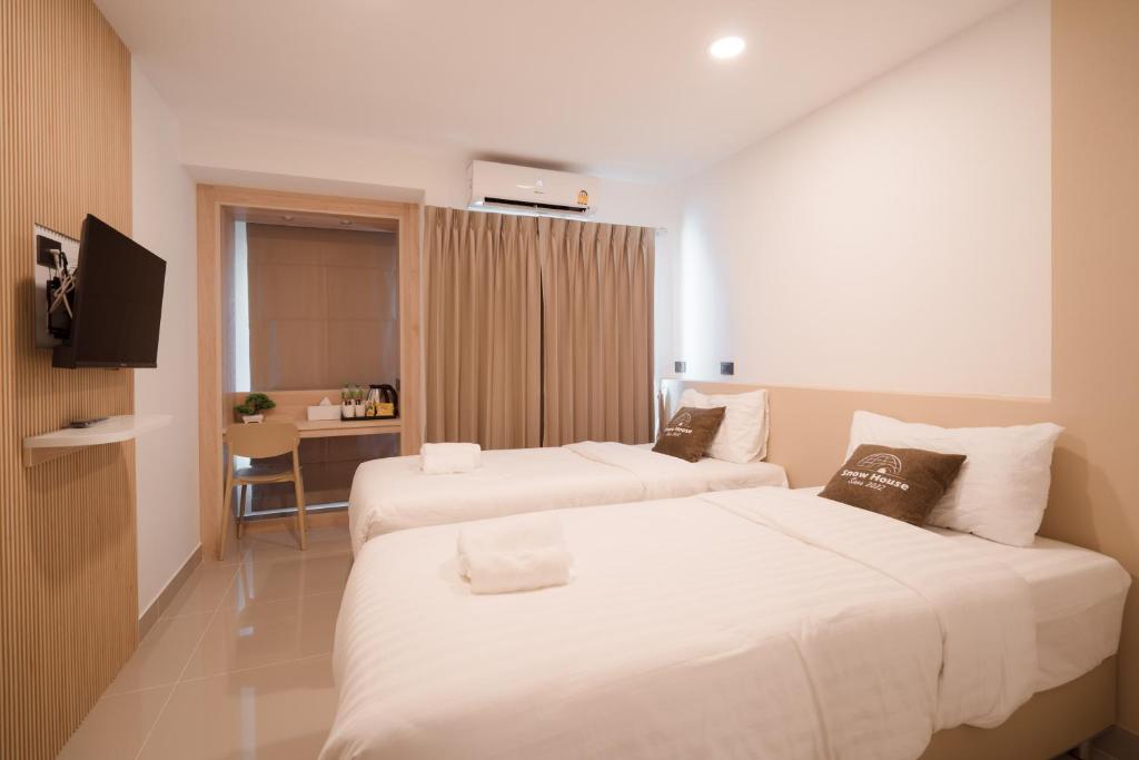 a hotel room with two beds and a desk at SNOW HOUSE Buriram in Buriram