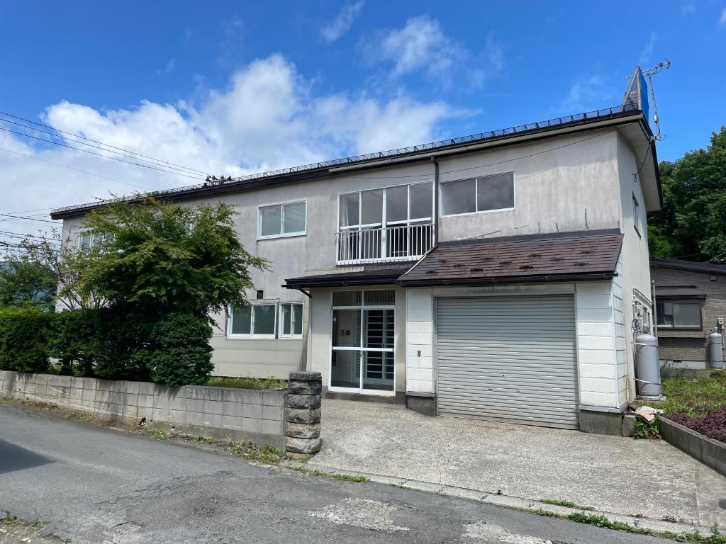 une grande maison blanche avec un garage dans l'établissement 松ノ木ハウス, à Nobeji