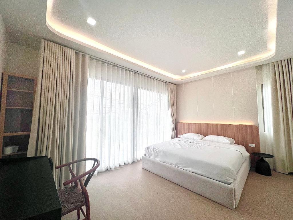 ein Schlafzimmer mit einem Bett und einem großen Fenster in der Unterkunft Cozy Maison in Ban Bang Rathuk