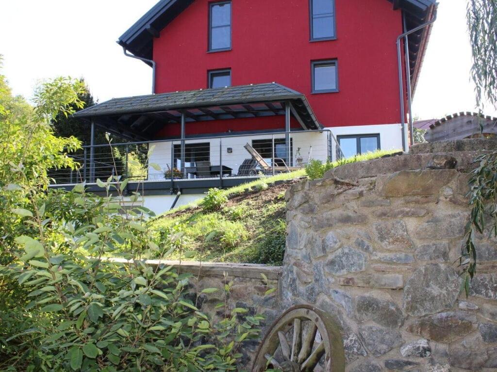 a red and white house with a stone wall at Jäschner Villa Luftig in Remptendorf