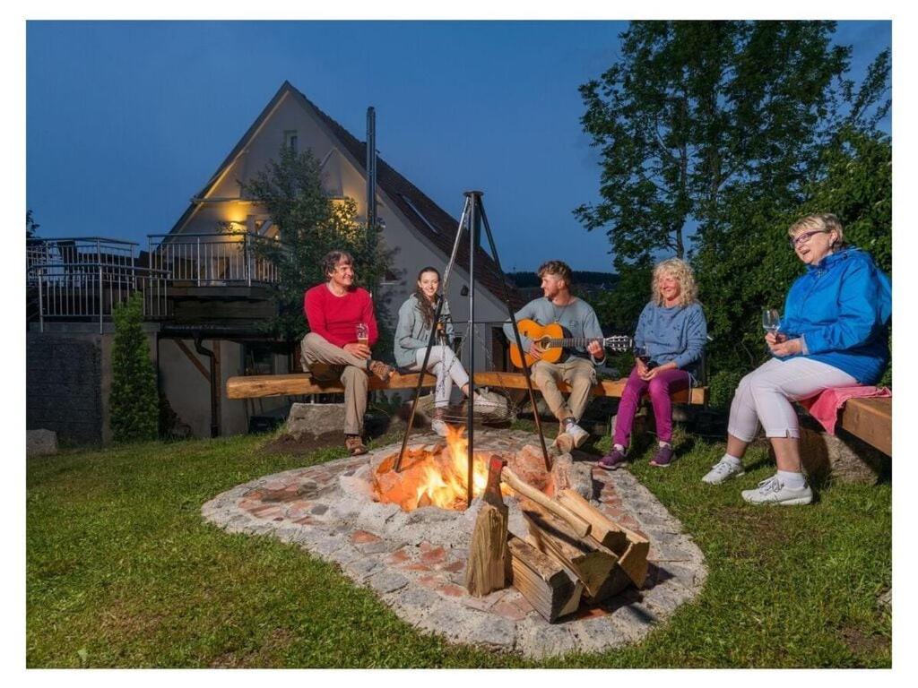 grupa ludzi siedzących wokół ogniska w obiekcie To the cuckoo Black Forest w mieście Schonach im Schwarzwald