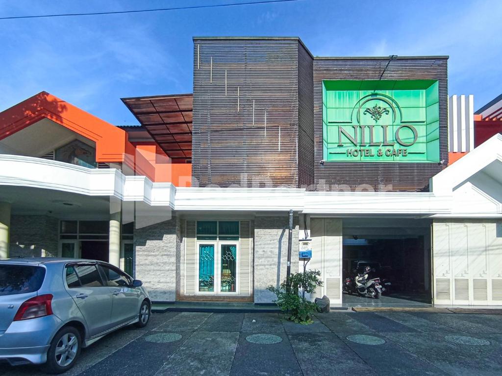 a car parked in a parking lot in front of a building at Nillo Hotel Kebumen Mitra RedDoorz in Kebumen
