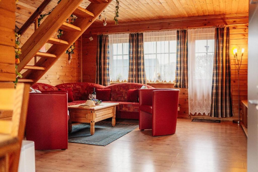 a living room with red couches and a table at idyllisch gelegenes Blockhaus - Hunde willkommen in Bad Sachsa