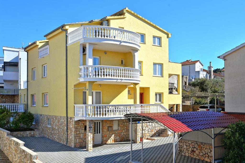 - un bâtiment jaune avec des balcons blancs dans l'établissement Apartments Goranka 2, à Murter