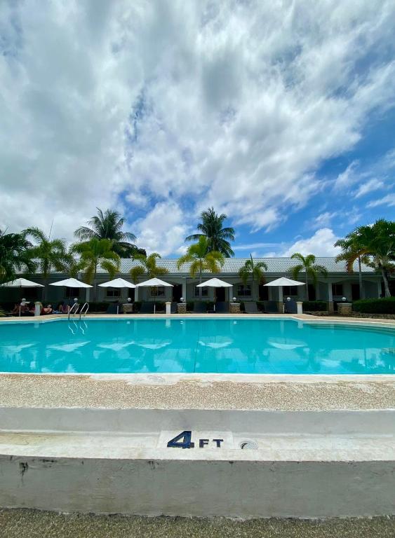 a large swimming pool with palm trees and umbrellas at Panglao Regents Park Resort in Panglao Island