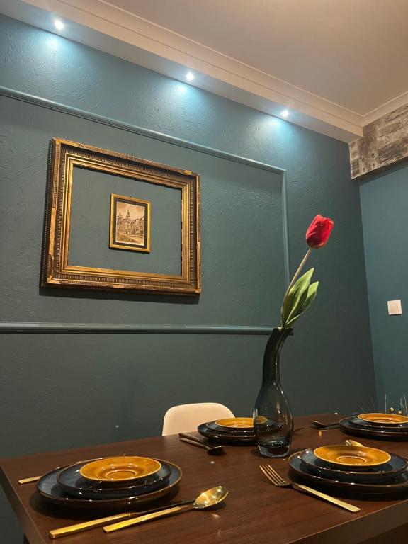 a table with plates and a vase with a rose at Apartament Baron II ***** in Jelenia Góra