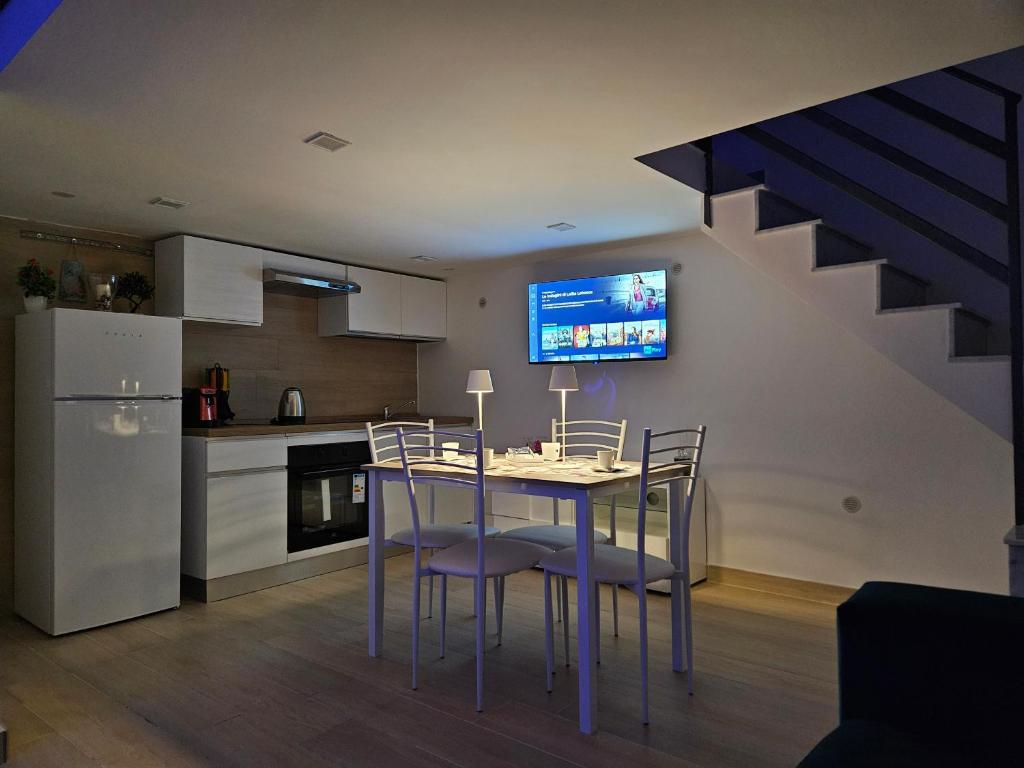 a kitchen with a table with chairs and a tv on the wall at Casa savoia dream in Naples