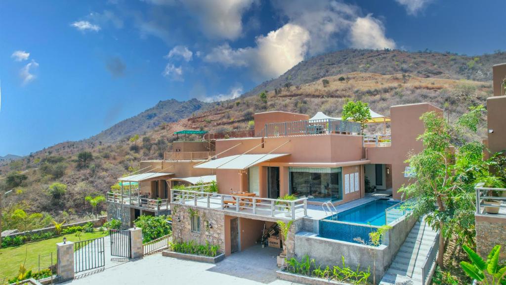 an image of a house with a mountain in the background at SaffronStays Moringa Wishing Tree in Udaipur