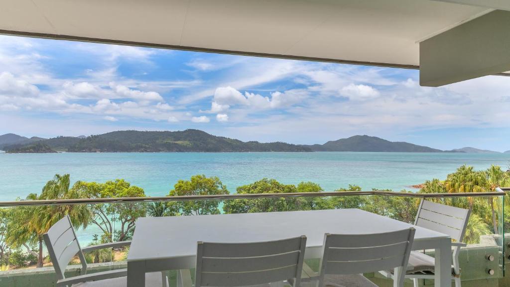 a table and chairs on a balcony with a view of the ocean at Lagoon Beachfront Lodge 202 on Hamilton Island by HamoRent in Hamilton Island