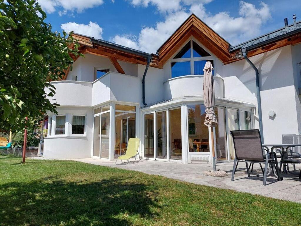 a white house with a patio with chairs and an umbrella at Michl"s Villa Modern retreat in Tarrenz