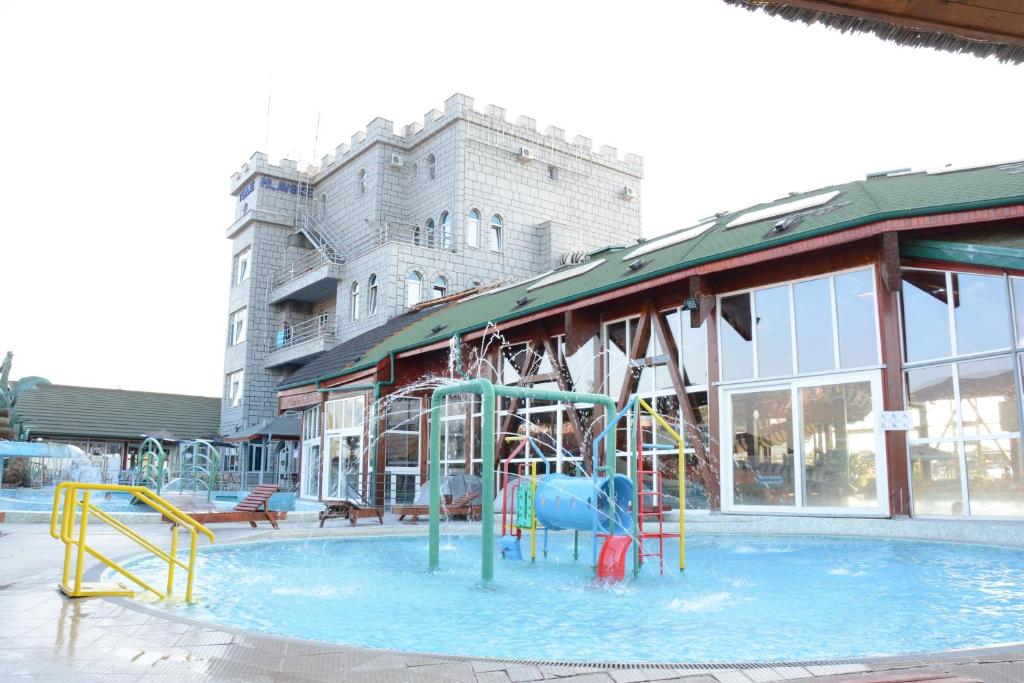 una piscina con parque infantil frente a un edificio en Hotel Mlavske Terme Ždrelo, en Ždrelo