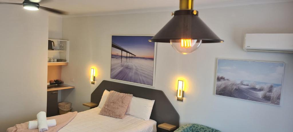 a bedroom with a bed and a ceiling fan at Golden Sands Motor Inn in Forster