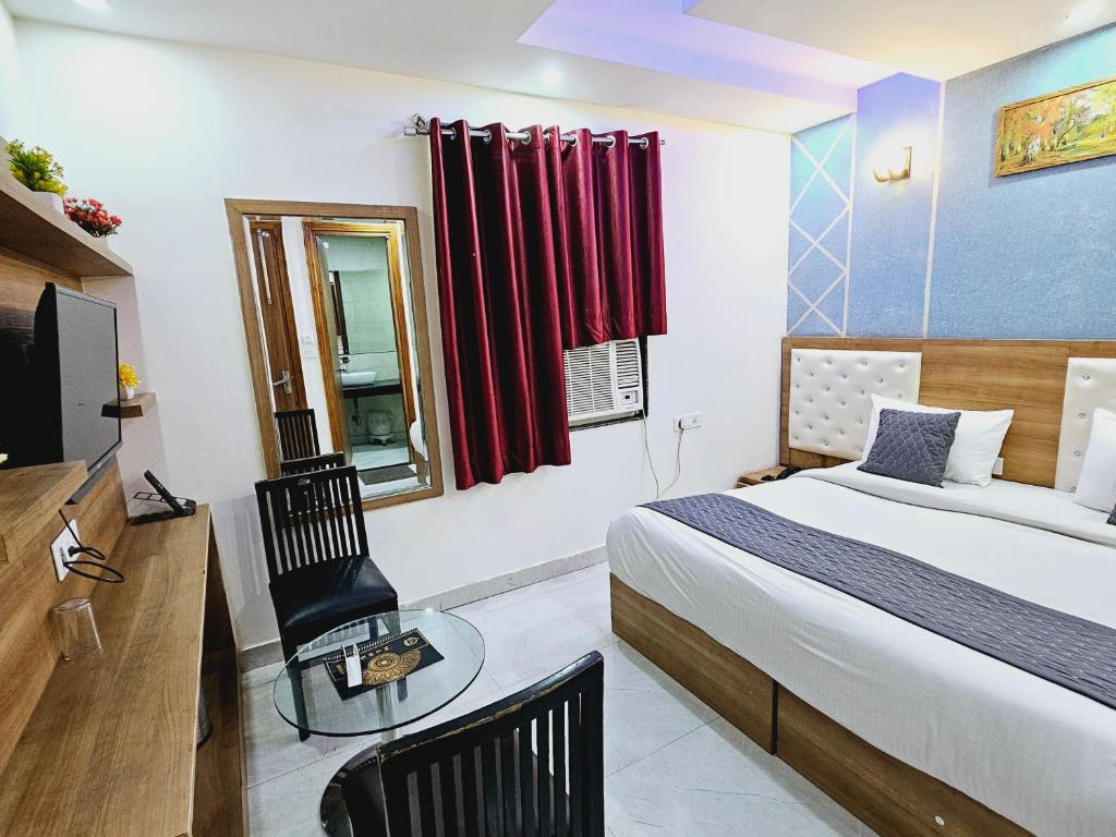 a bedroom with a bed and a table and a television at Hotel TU Casa (Stay near International Airport) in New Delhi