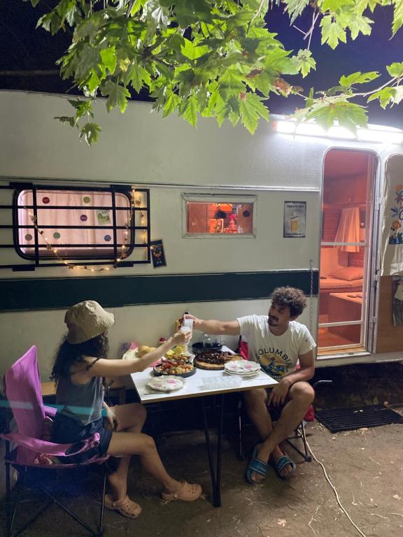 2 personnes assises à une table devant une caravane dans l'établissement Caravan camp, à Erdemli