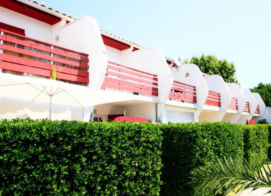 un bâtiment avec des sièges rouges et une haie dans l'établissement Green Village - Deux pièces mezzanine résidence avec piscine MAE-2004, à La Grande Motte