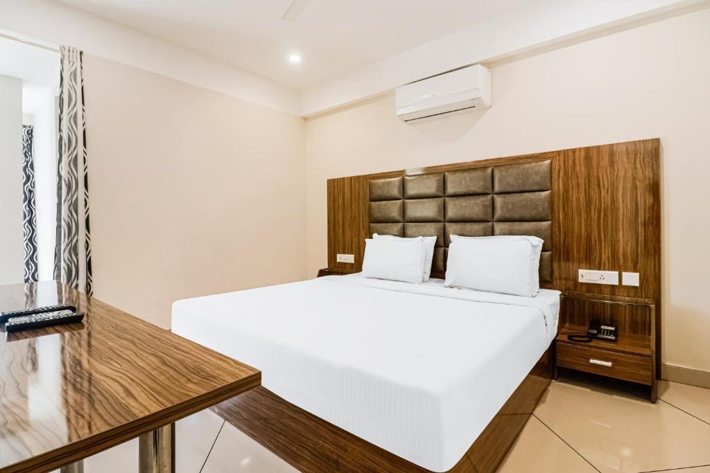 Schlafzimmer mit einem großen weißen Bett und einem Kopfteil aus Holz in der Unterkunft Super Capital O Edassery Resort in Kattappana