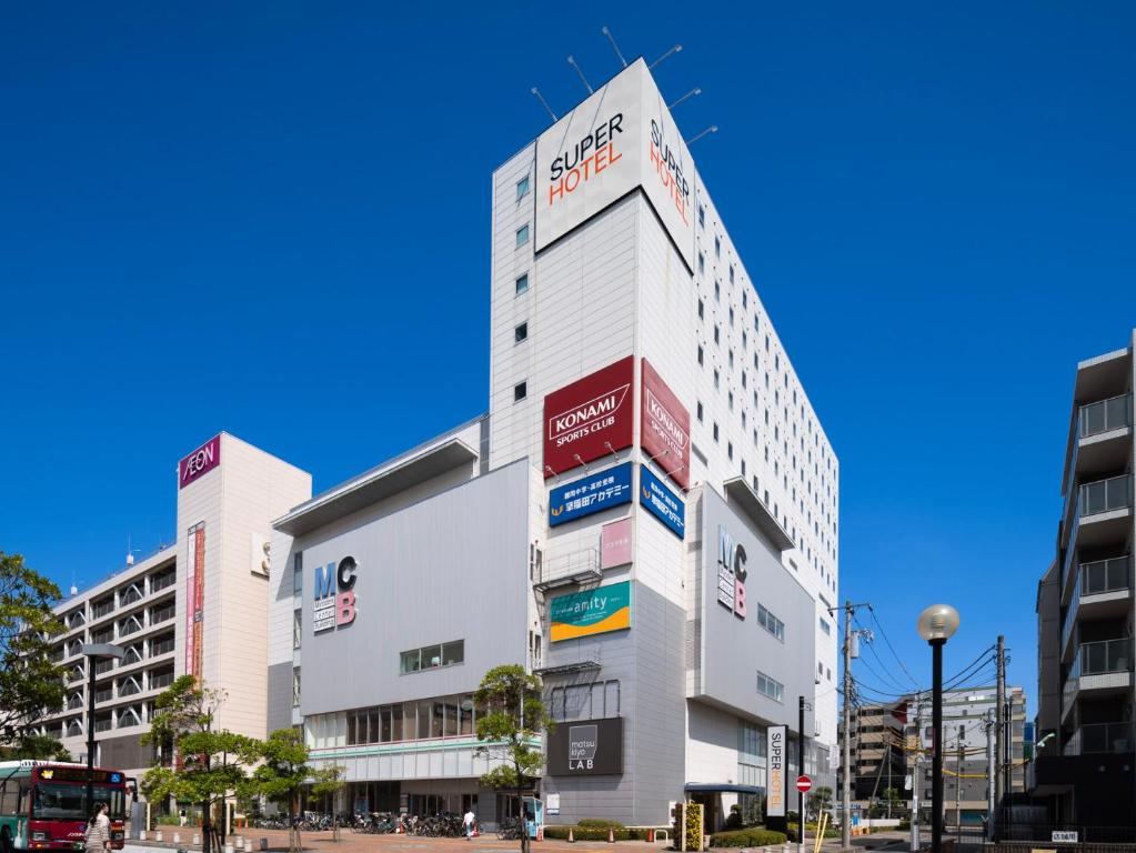 Un grand bâtiment blanc avec de nombreux panneaux. dans l'établissement Super Hotel Tozai line Ichikawa Myoden Ekimae, à Ichikawa