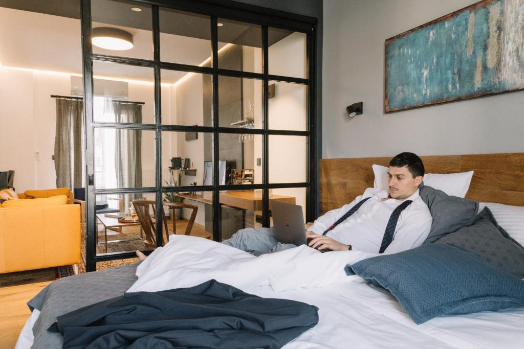 a man laying in a bed with a laptop at The 4 Travellers Thessaloniki in Thessaloniki