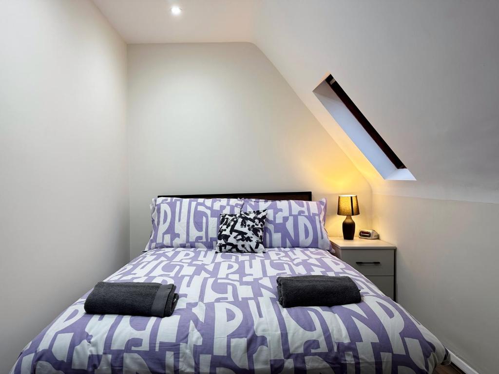 a bedroom with a bed with a purple and white bedspread at Natalie’s Apartment in Wembley in London