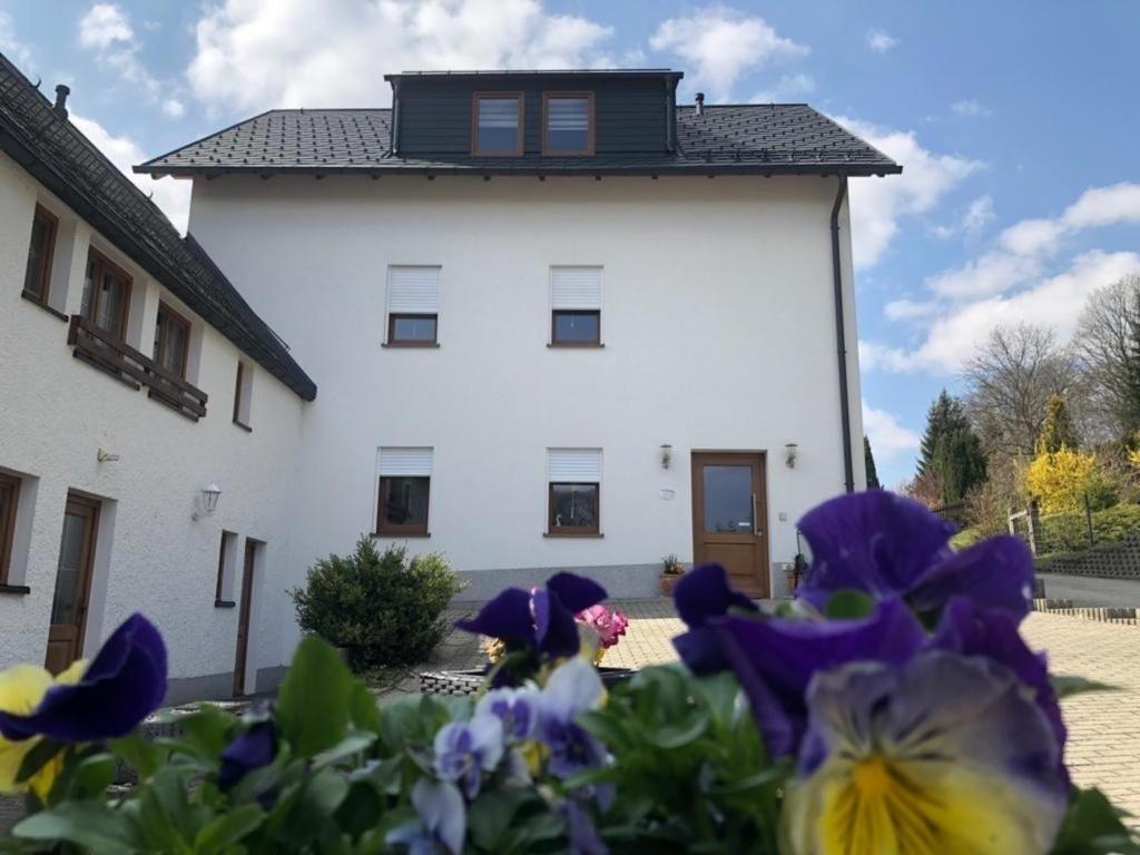 ein weißes Gebäude mit lila Blumen davor in der Unterkunft Seniorenfreundliche und behindertengerechte Erdgeschosswohnung mit hohem Komfort für drei Personen in Bad Brambach