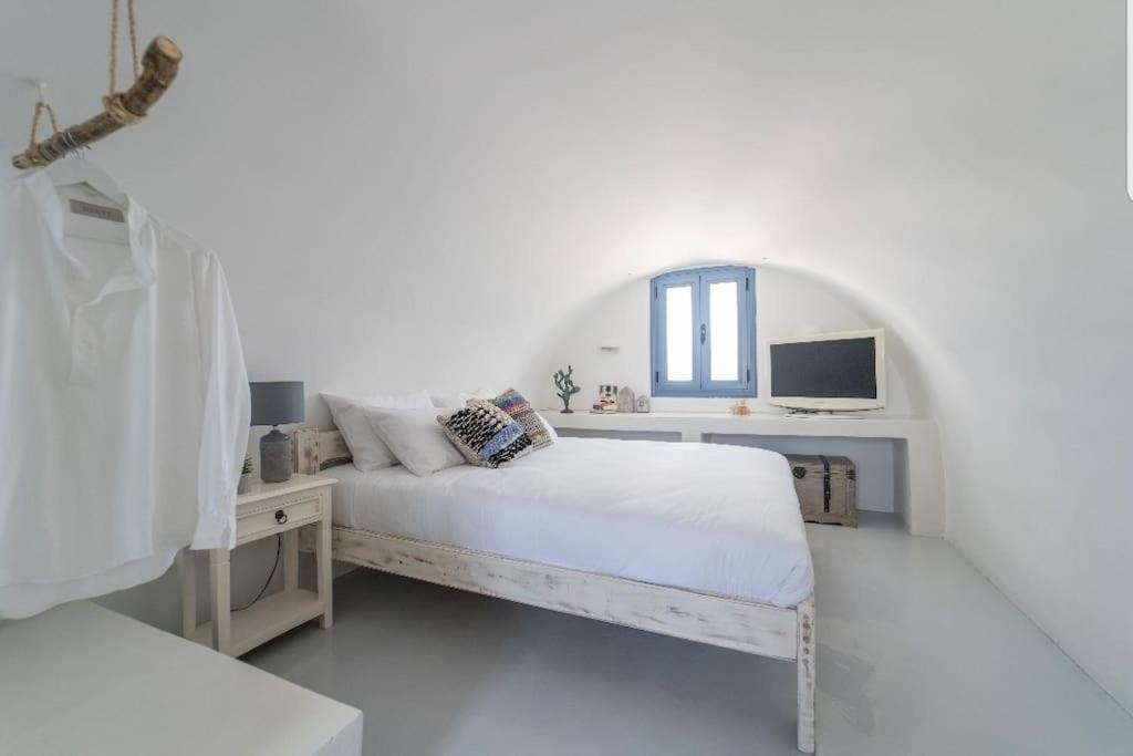 una camera da letto bianca con un letto e una finestra di Dome suite,hot tub,sea view in Firostefani! a Firà
