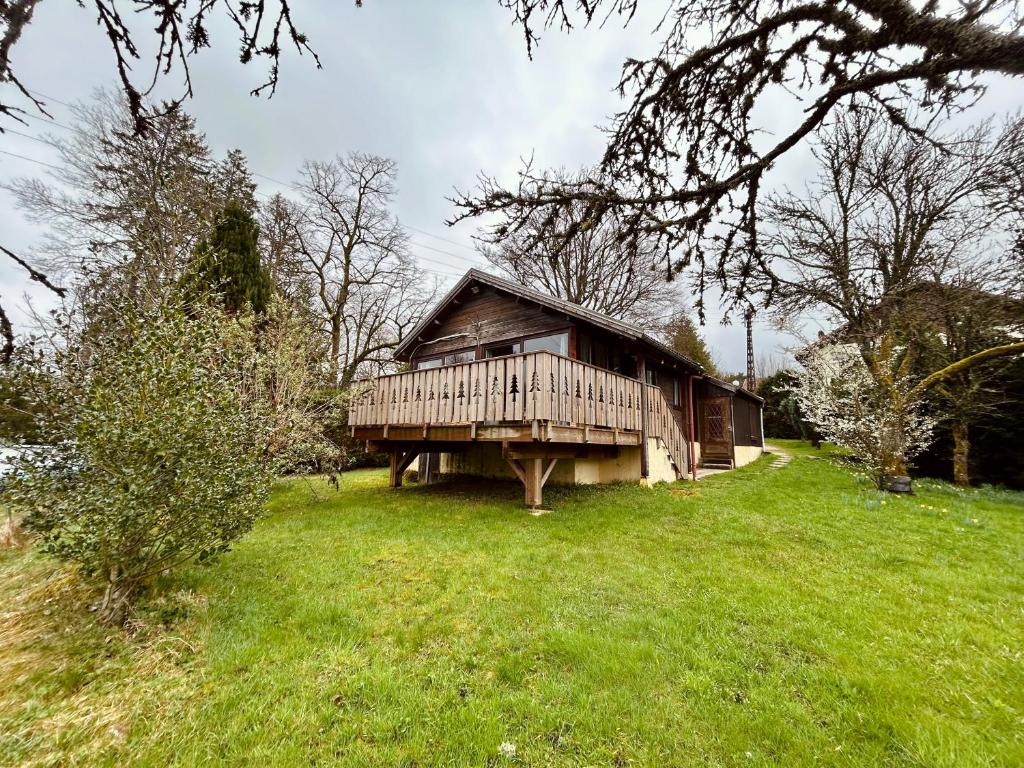 a wooden cabin in a grassy field next to a tree at Au Chalet d'Aline - Atypique pour 4 personnes in Gérardmer