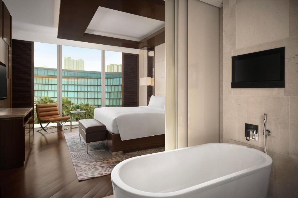 a bathroom with a tub and a bedroom with a bed at JW Marriott Hotel Hanoi in Hanoi