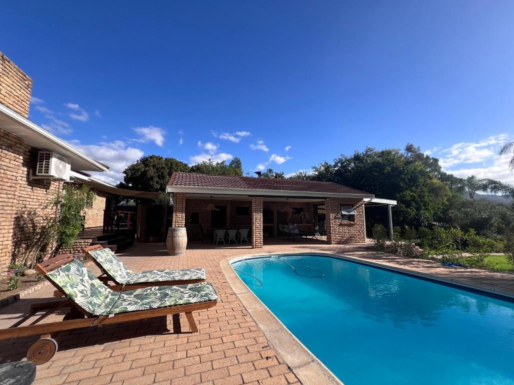 a swimming pool with two lounge chairs next to a house at Aan d'Oewer in Citrusdal