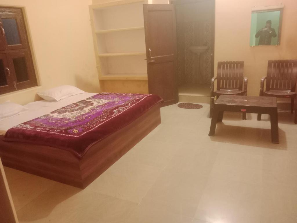 sypialnia z łóżkiem i 2 krzesłami w obiekcie Aanand Bhwan dharmshala ayodhya w mieście Ayodhya