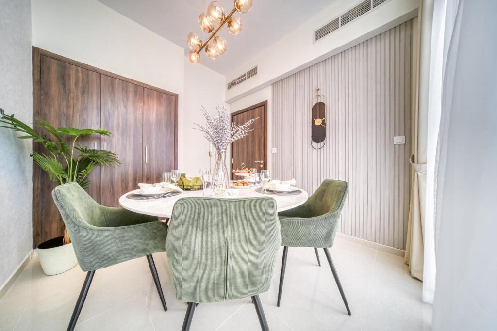 ein Esszimmer mit einem Tisch und grünen Stühlen in der Unterkunft Autumn Serenity Manor: Luxury 3 Bedroom Townhouse in Dubai