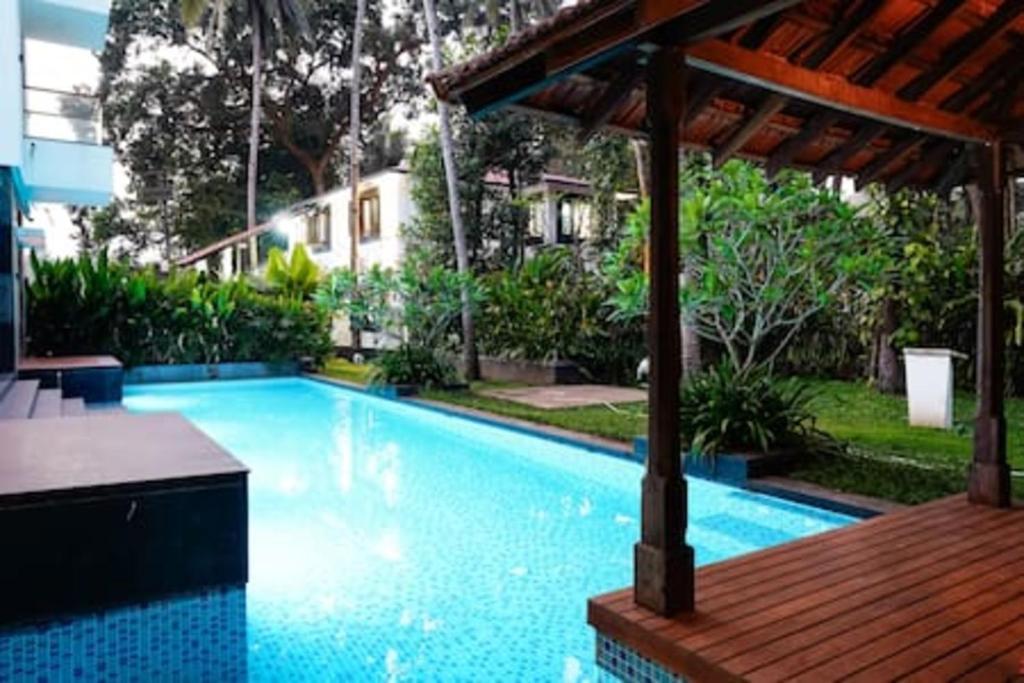 uma piscina com um deque de madeira ao lado de um edifício em Casa Verde · Luxurious 3BHK Villa in Goa Velha em Goa