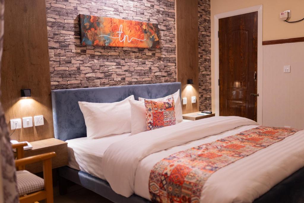 1 dormitorio con 1 cama grande y pared de ladrillo en The nexus Hotel Apartments, en Peshawar