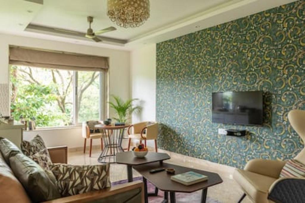 een woonkamer met een bank en een tv aan de muur bij Luxurious Apartment with a Pool near Candolim 11 in Goa