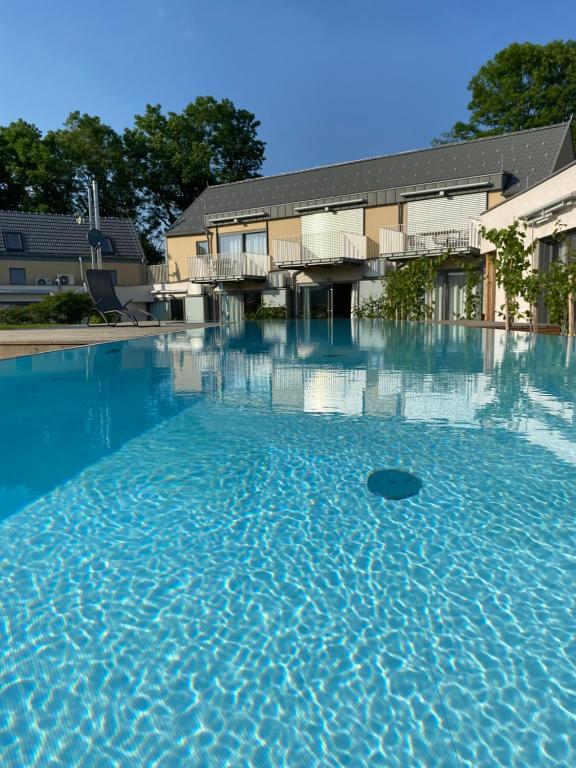 a large pool of blue water in front of a building at Paradies in den Südsteirischen Weinbergen: Bezauberndes Apartment mit Terrasse, Infinity Pool-Zugang, Sauna und Fitnessbereich! in Obegg