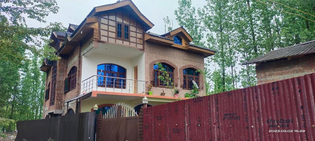 a house with a red fence in front of it at Moonlight Homestay Gulmarg in Srinagar