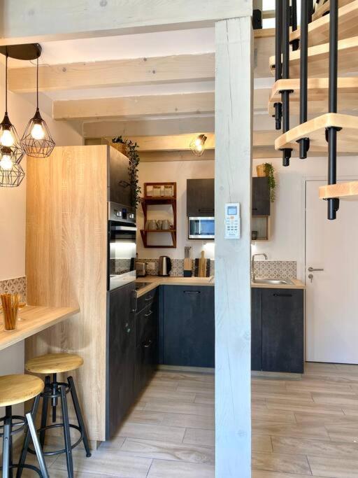 une grande cuisine avec des placards noirs, des tables et des chaises dans l'établissement Villa Maya 5 - Aglandau - AVIGNON - CLIM - WIFI, à Avignon