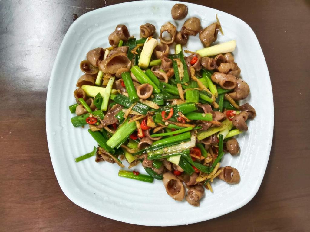 um prato branco de alimentos com cogumelos e produtos hortícolas em Hotel ĐUC THANH VINH em Củ Chi